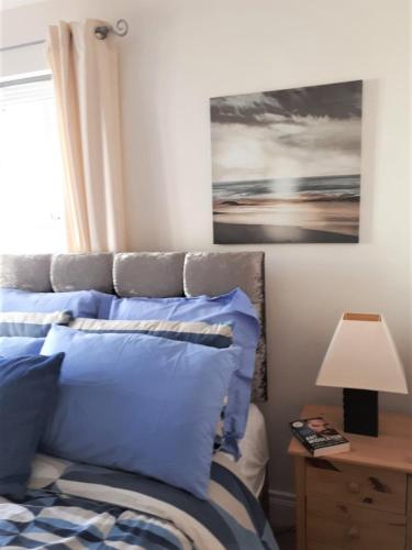a bedroom with a bed with blue pillows and a painting at Rock Quay in Killyleagh