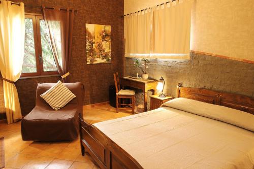 a bedroom with a bed and a chair and a desk at Hotel Alle Pendici in Nicolosi