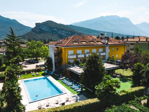 un hotel con piscina y montañas de fondo en Hotel Campagnola, en Riva del Garda