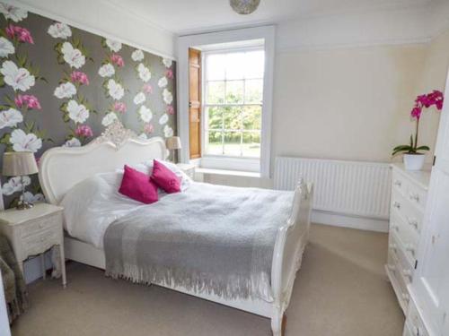 een slaapkamer met een bed met roze kussens en een raam bij Bridge End Cottage in Carnforth