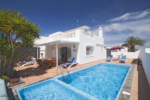 eine Villa mit einem Pool vor einem Haus in der Unterkunft Casa Jasmine - lovely Los Mojones villa WiFi heated pool short walk to beach in Puerto del Carmen