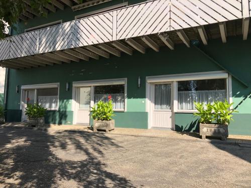 a green building with two doors and potted plants at Wildkräuter-Gasthof Linde in Löffingen