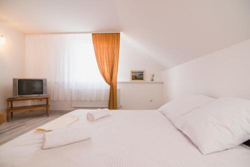 een witte slaapkamer met een bed en een televisie bij Margit Sziget in Svaliava