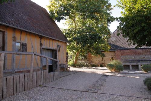 a barn with a wooden door next to a building at Le Jardin Découverte in Conches-en-Ouche