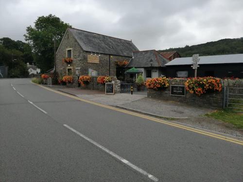 un camino vacío frente a un edificio con flores en Sgwd Gwladys Lodge en Pont-Nedd-Fechan