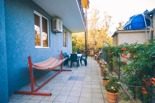 a blue house with a hammock on a patio at Makos Guest House in Kutaisi