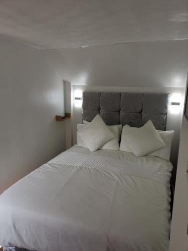 a bed with white sheets and pillows in a bedroom at Glenfern Guest House and a separate Cottage with its own private hot tub in Balloch