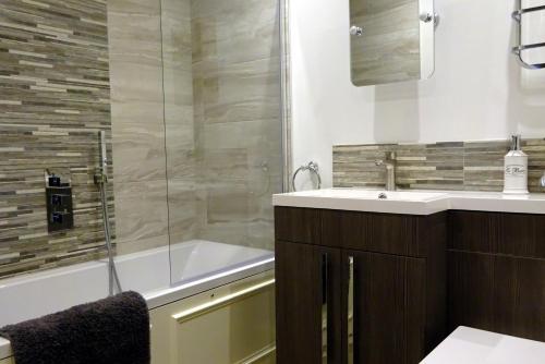 y baño con bañera, lavamanos y ducha. en Derwent View Holiday Apartments en Matlock