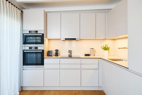 a kitchen with white cabinets and a sink at Fuchsbau Romantik Hotel & SPA Restaurant & FOX Bar in Timmendorfer Strand