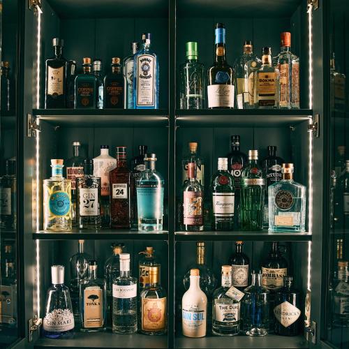 a shelf filled with lots of bottles of alcohol at Fuchsbau Romantik Hotel & SPA Restaurant & FOX Bar in Timmendorfer Strand