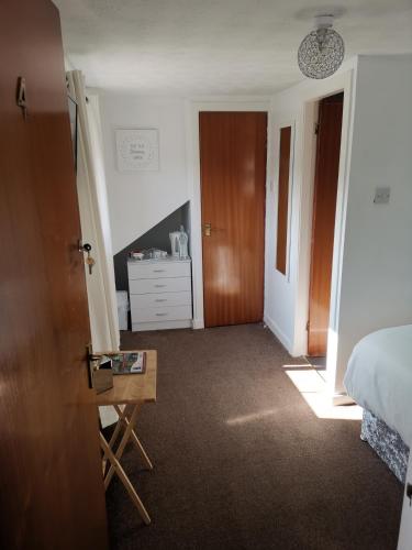 a bedroom with a bed and a table and a door at Glenfern Guest House and a separate Cottage with its own private hot tub in Balloch