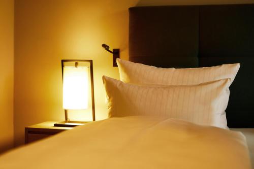 a bed with a white pillow and a lamp at Fuchsbau Romantik Hotel & SPA Restaurant & FOX Bar in Timmendorfer Strand