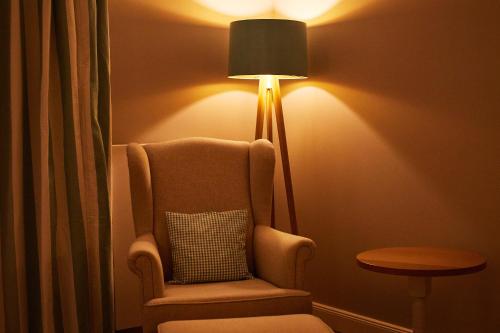 a room with a chair and a lamp with a pillow at Fuchsbau Romantik Hotel & SPA Restaurant & FOX Bar in Timmendorfer Strand