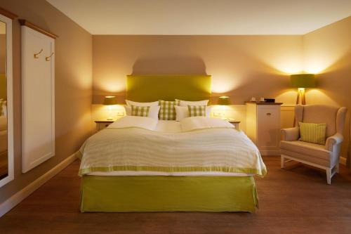 a bedroom with a large bed and a chair at Fuchsbau Romantik Hotel & SPA Restaurant & FOX Bar in Timmendorfer Strand