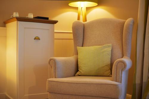 a chair with a green pillow sitting next to a lamp at Fuchsbau Romantik Hotel & SPA Restaurant & FOX Bar in Timmendorfer Strand