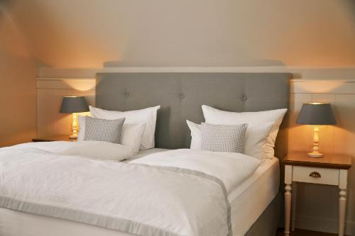 a bedroom with two beds with white sheets and two lamps at Fuchsbau Romantik Hotel & SPA Restaurant & FOX Bar in Timmendorfer Strand
