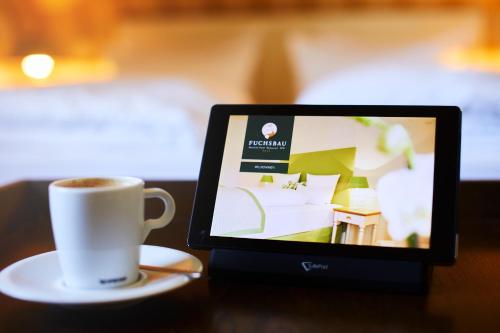 a cup of coffee and a tablet on a table at Fuchsbau Romantik Hotel & SPA Restaurant & FOX Bar in Timmendorfer Strand