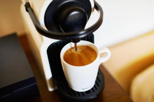 a coffee maker is making a cup of coffee at Fuchsbau Romantik Hotel & SPA Restaurant & FOX Bar in Timmendorfer Strand
