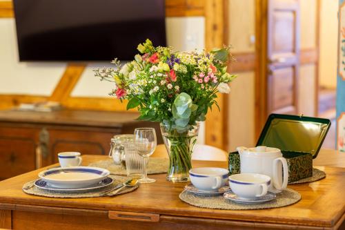 a wooden table with a vase of flowers and cups at Apartments No 126 Loket in Loket