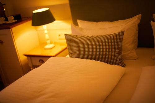 a bed with a pillow and a lamp on a table at Fuchsbau Romantik Hotel & SPA Restaurant & FOX Bar in Timmendorfer Strand
