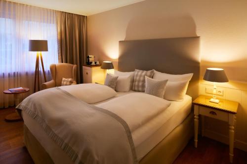 ein Hotelzimmer mit einem großen Bett und einem Stuhl in der Unterkunft Romantik Hotel Fuchsbau in Timmendorfer Strand
