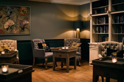 a waiting room with chairs and a table and books at Fuchsbau Romantik Hotel & SPA Restaurant & FOX Bar in Timmendorfer Strand