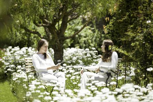 two women sitting on a bench in a garden at Hotel La Casona De Yucay Valle Sagrado in Urubamba