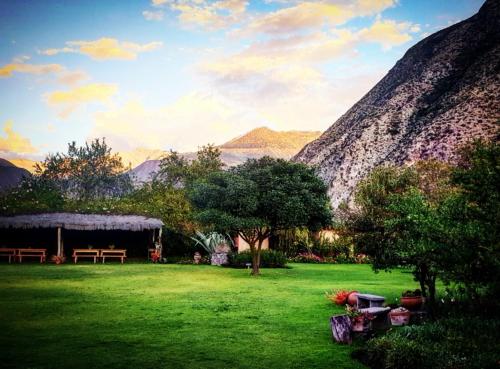 a green yard with a picnic table and mountains in the background at Hotel La Casona De Yucay Valle Sagrado in Urubamba