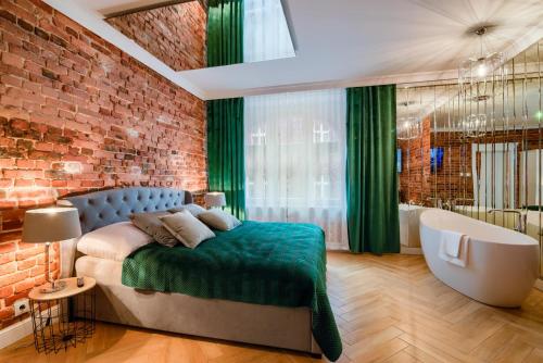 a bedroom with a brick wall and a bed and a bath tub at Fancy Apartment Nikiszowiec in Katowice