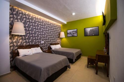 a hotel room with two beds and a green wall at Hotel Santa Rosa by Rotamundos in Cholula