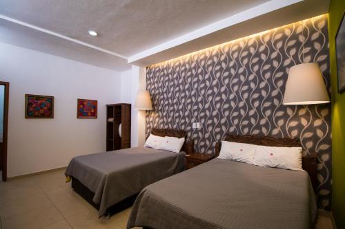 a hotel room with two beds and a wall at Hotel Santa Rosa in Cholula