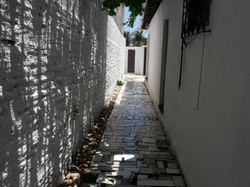 a narrow alley with a stone wall and a building at Paracuru HolaOnda WaveHostel in Paracuru