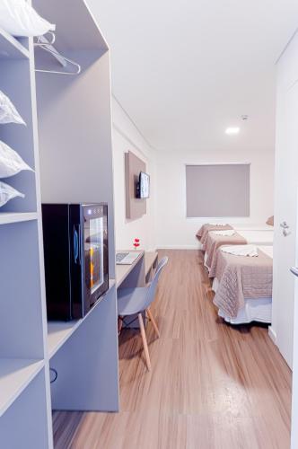 a room with two beds and a desk and a tv at Prime Hotel Ponta Porã in Ponta Porã