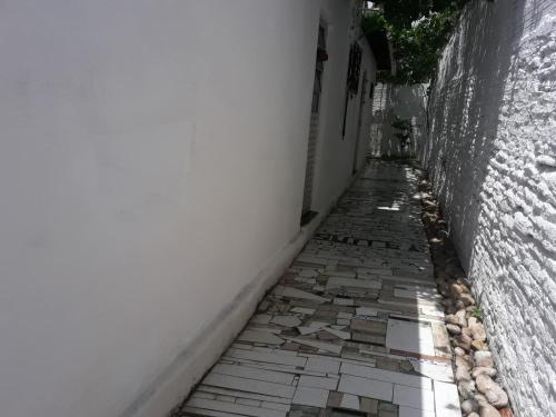 an alley way with a white wall and a stone sidewalk at Paracuru HolaOnda WaveHostel in Paracuru
