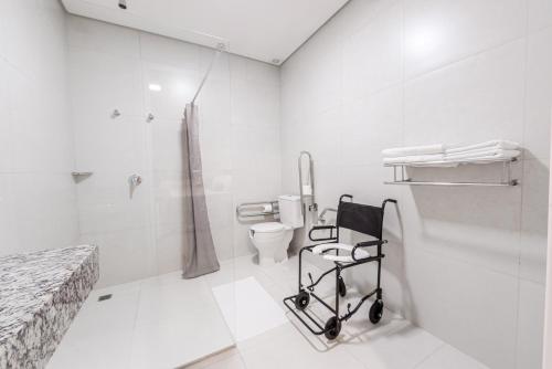 a white bathroom with a toilet and a walk in shower at Prime Hotel Ponta Porã in Ponta Porã