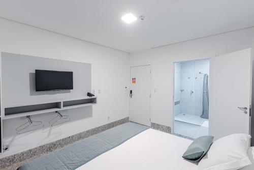 a white bathroom with a tv and a shower at Prime Hotel Ponta Porã in Ponta Porã