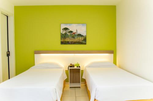 2 Betten in einem Zimmer mit grünen Wänden in der Unterkunft Bristol Upper Curitiba Alto da XV in Curitiba