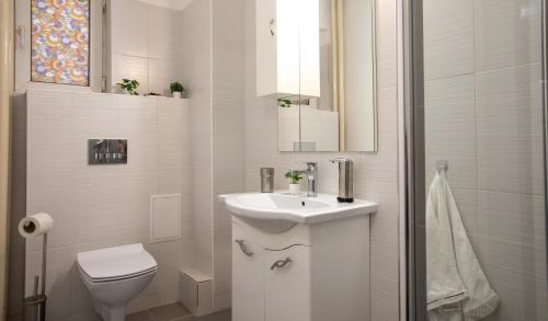 a white bathroom with a sink and a toilet at Aquarium Apartment Grivita in Bucharest