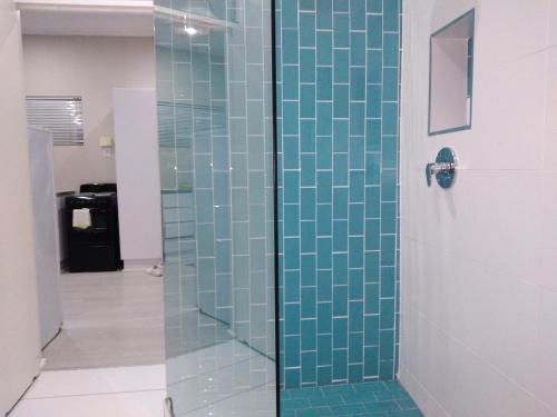 um chuveiro com azulejos de vidro azul na casa de banho em 901 Umdloti Beach Resort em Umdloti