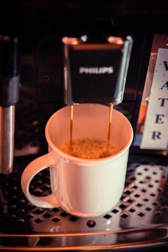 a cup of coffee is being made in a coffee machine at Wood House Republicii in Braşov