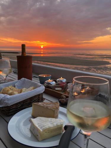 une table avec une assiette de fromage et un verre de vin dans l'établissement Les pieds dans l'eau, à Blonville-sur-Mer