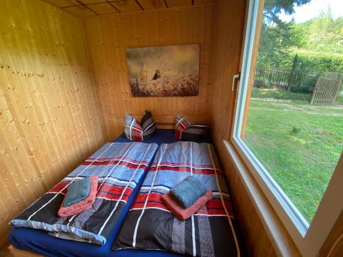 Bett in einem kleinen Zimmer mit Fenster in der Unterkunft Waldfrieden Bungalow in Garnsdorf