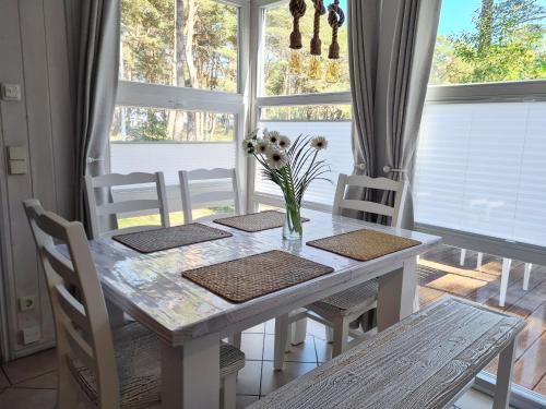 a dining room table with a vase of flowers on it at Strandhaus Rügen - Meerblick, Sauna, Kamin & Whirlpool in Baabe