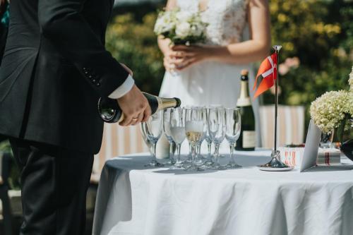 a man pouring champagne into wine glasses on a table at Bøgebjerggård Bed & Breakfast in Nordborg