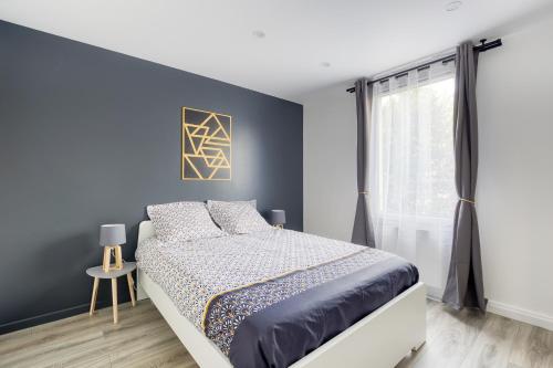 um quarto com uma cama e uma parede azul em J-Mo Home - Magny - Moderne et chaleureux em Magny-le-Hongre