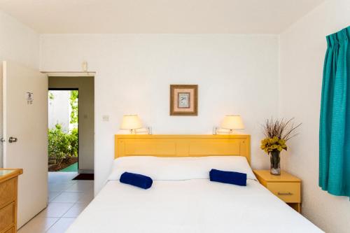 a bedroom with a white bed with blue pillows at Plum Tree Club in Bridgetown