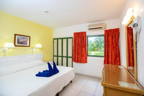 a bedroom with a bed and a window with red curtains at Plum Tree Club in Bridgetown