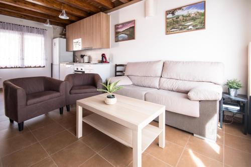 a living room with a couch and two chairs and a table at Apartamentos LA PARRA in Buitrago del Lozoya