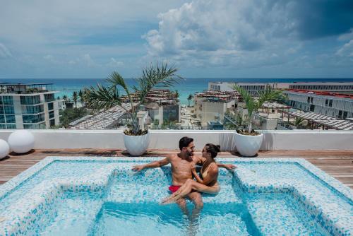 dos personas sentadas en una piscina en la parte superior de un hotel en The Reef 28 Hotel & Spa - Luxury Adults Only - All Suites - With Optional All Inclusive, en Playa del Carmen