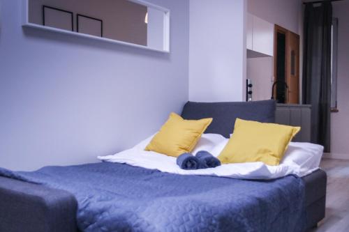 łóżko z niebieską pościelą i żółtymi poduszkami w obiekcie Apartamenty Długa 6 w Bydgoszczy
